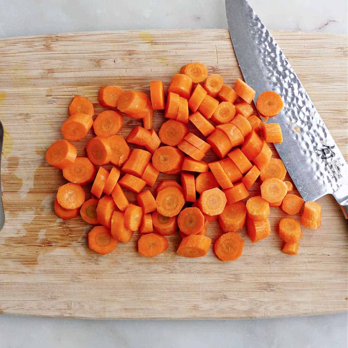 carrots cut into slices on a cutting board with a knife