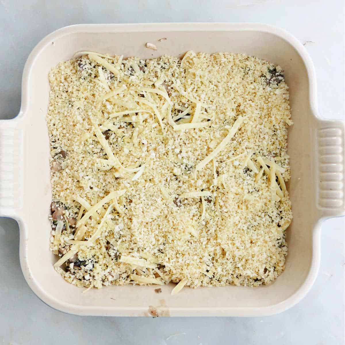 mushroom gratin filling topped with bread crumbs and cheese in a dish