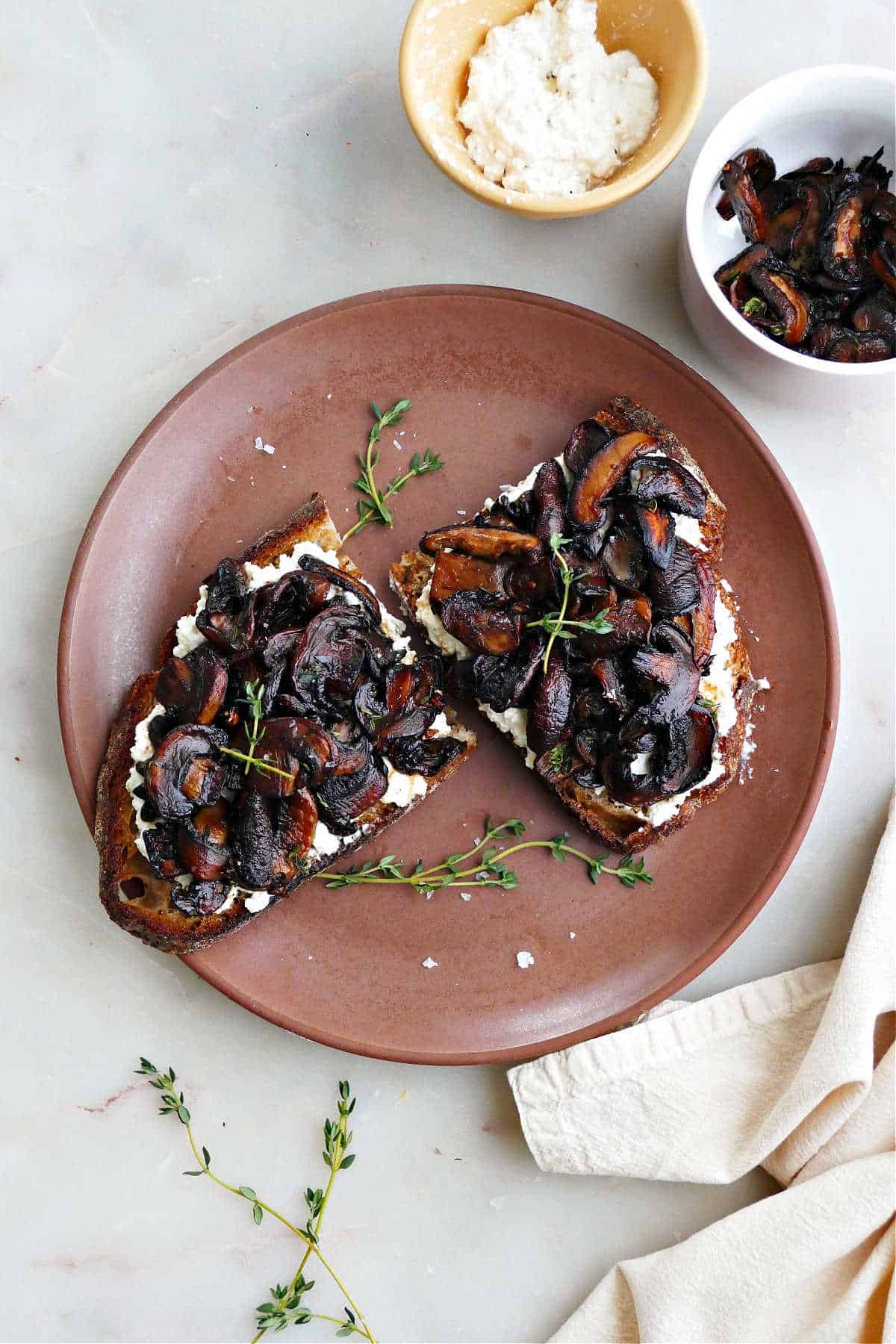 mushroom toast sliced in half on a serving plate