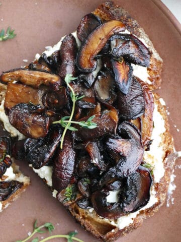 slice of mushroom ricotta toast with thyme sprigs on a serving plate