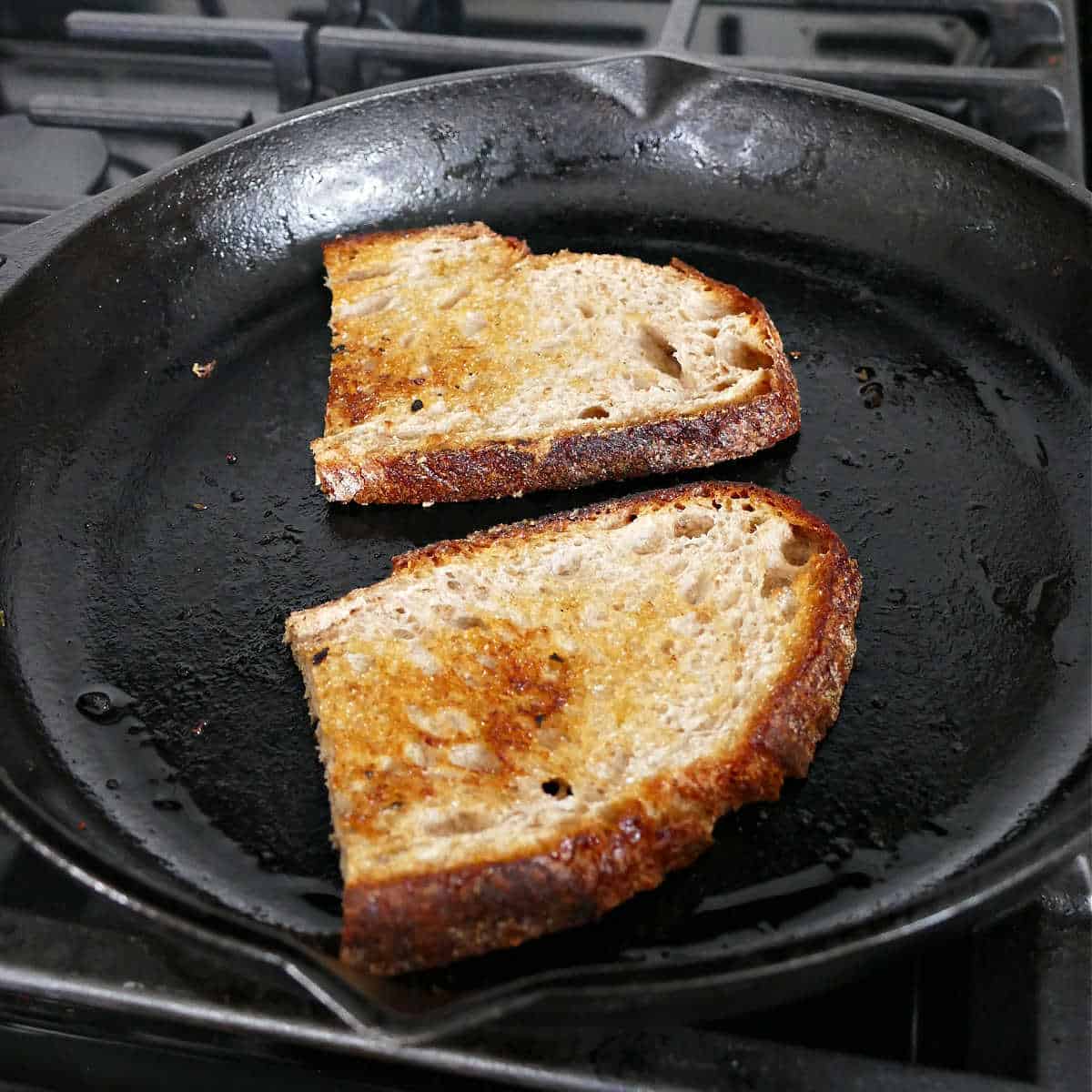 sourdough bread being toasted in a cast iron skillet on a stove