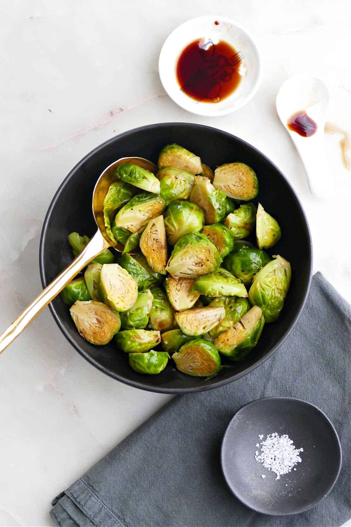 steamed Brussels sprouts in a serving bowl next to toppings