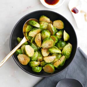 steamed Brussels sprouts in a serving bowl next to toppings
