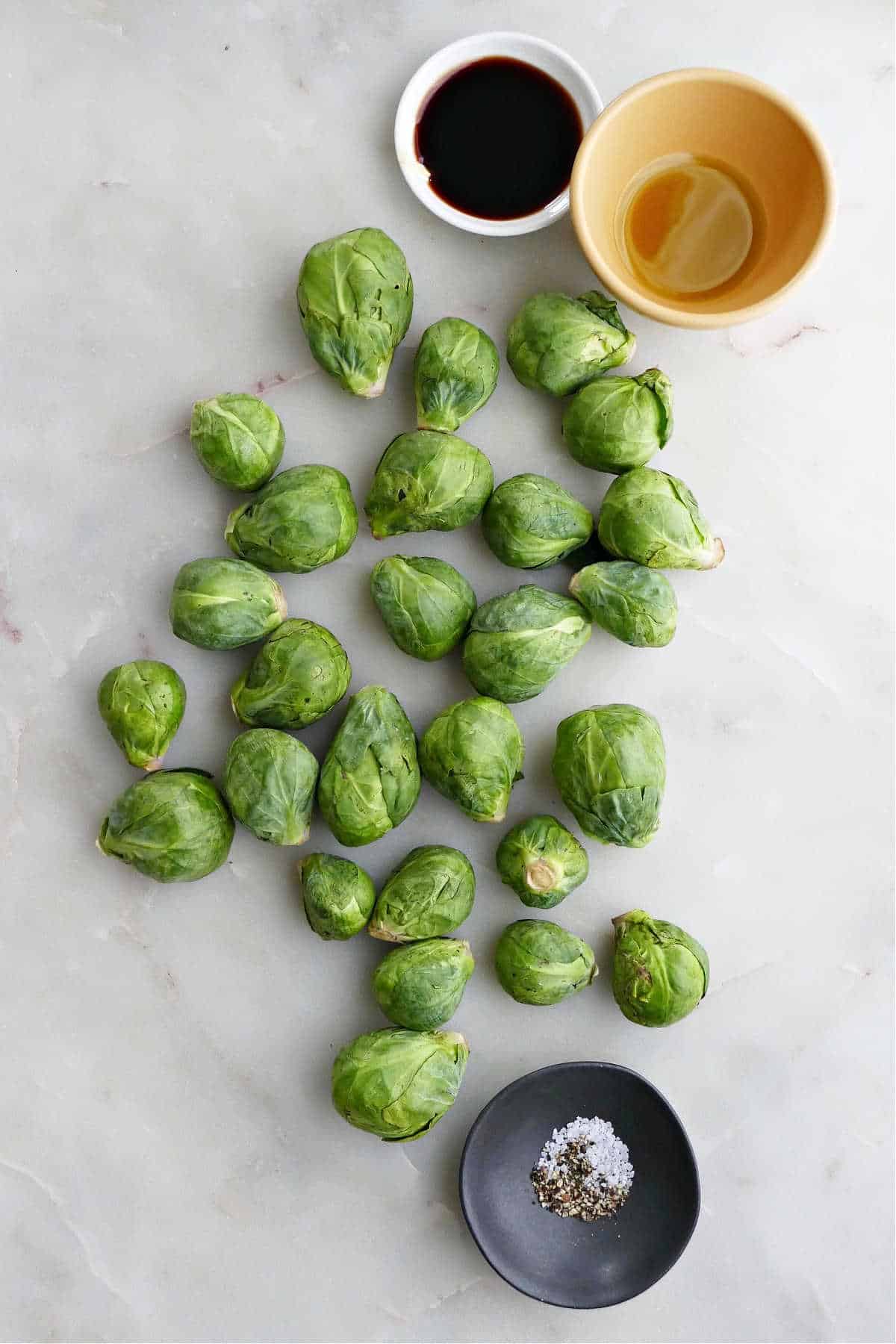 fresh Brussels sprouts on a counter next to seasonings