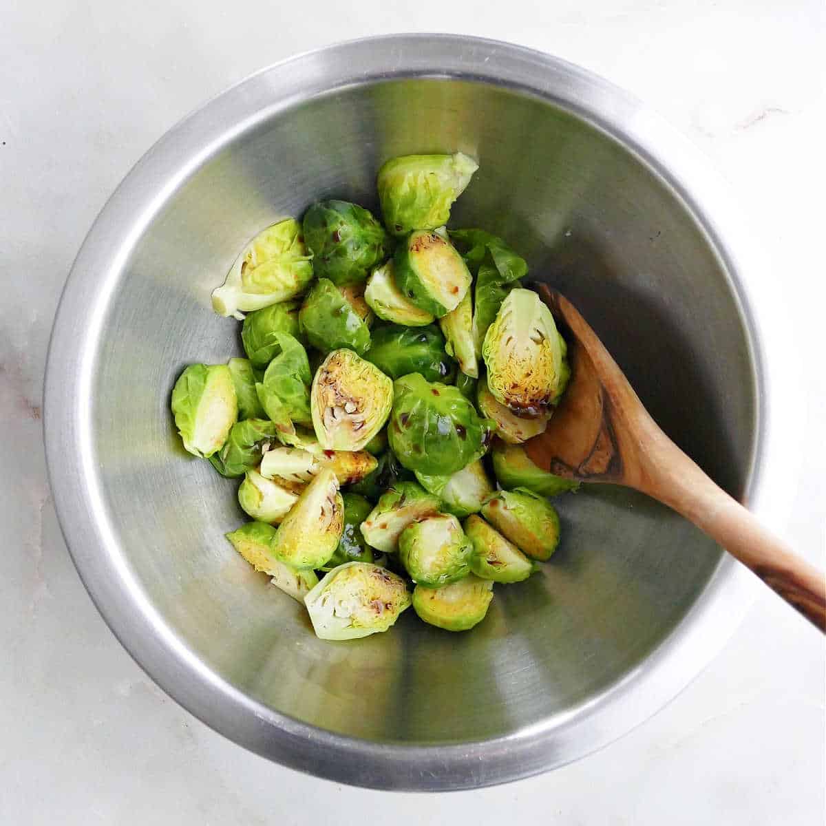 Brussels sprouts being mixed with balsamic vinegar in a bowl