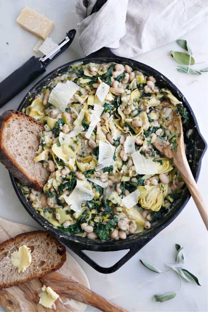 white bean skillet with parmesan, kale, and bread on a counter