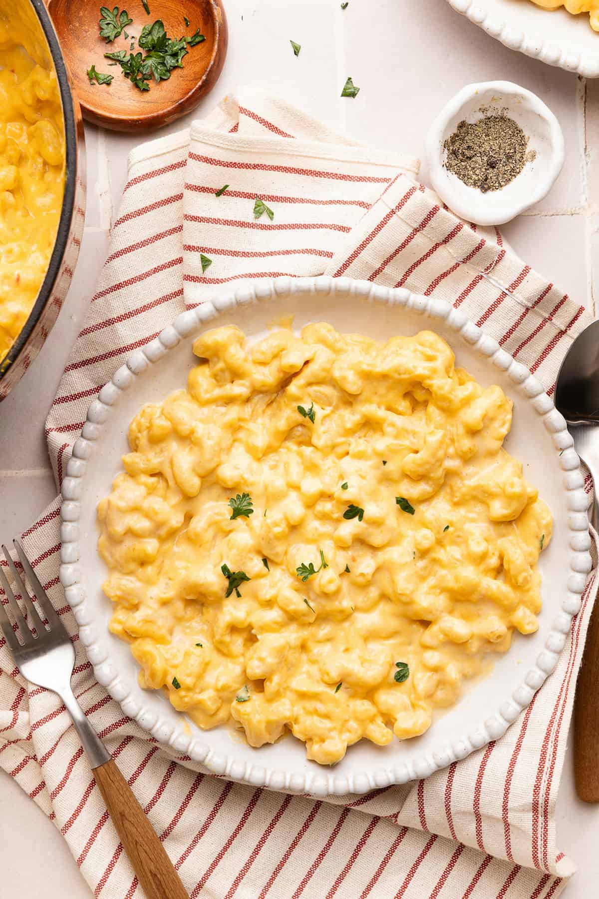 Veggie mac and cheese on a plate on a red striped napkin next to a fork.