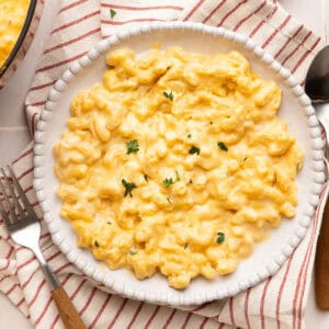 Veggie mac and cheese on a plate on a red striped napkin next to a fork.