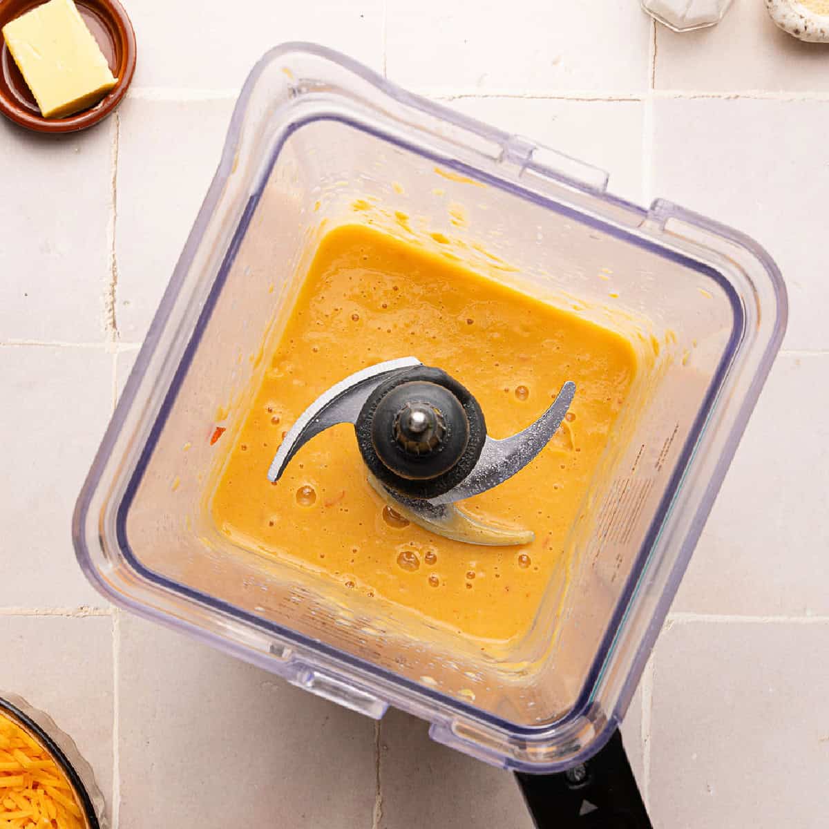 Blended mixed veggie and milk sauce in a blender on a counter.
