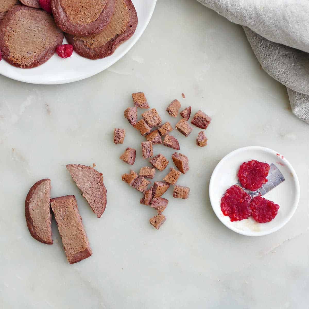 beet pancakes cut up into slices and pieces next to raspberries