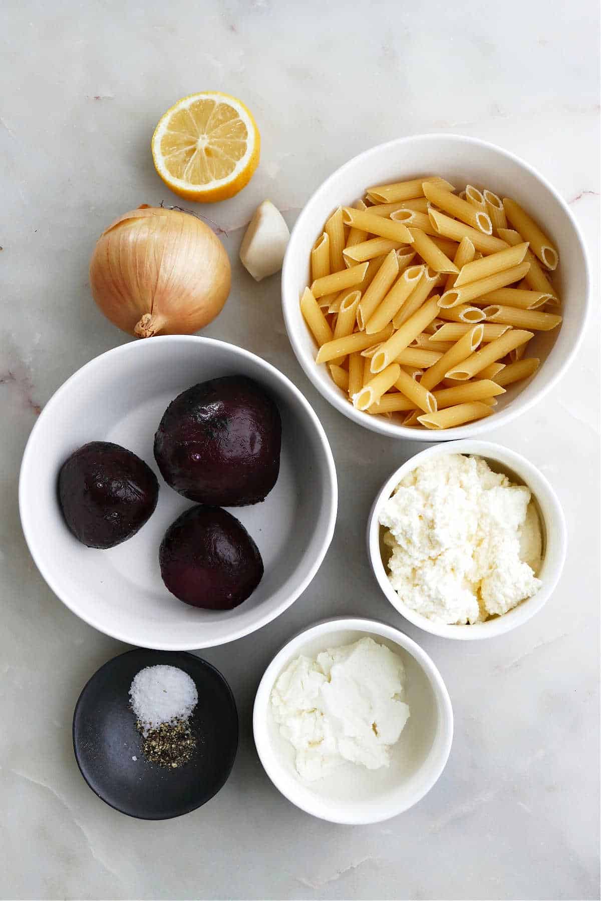 lemon, onion, garlic, beets, pasta, cheeses, salt, and pepper on a counter