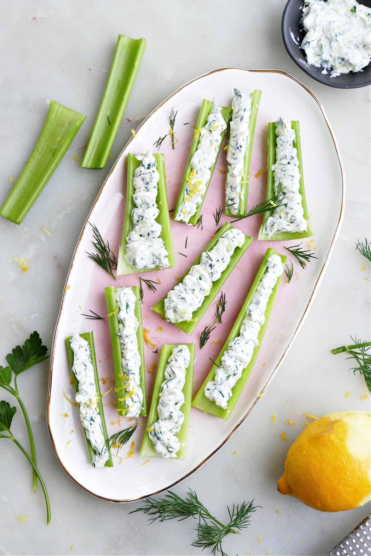 celery sticks stuffed with creamy cheese and herbs on a tray on a counter