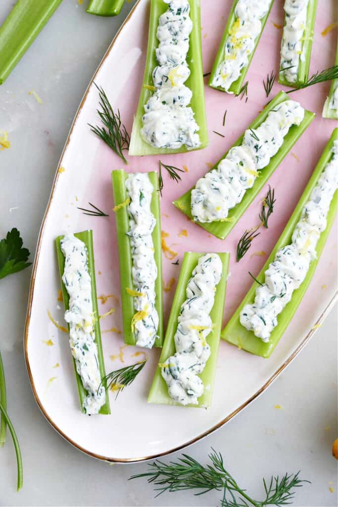 stuffed celery sticks on an oval serving tray sprinkled with herbs