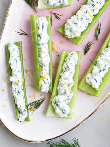 stuffed celery sticks on an oval serving tray sprinkled with herbs