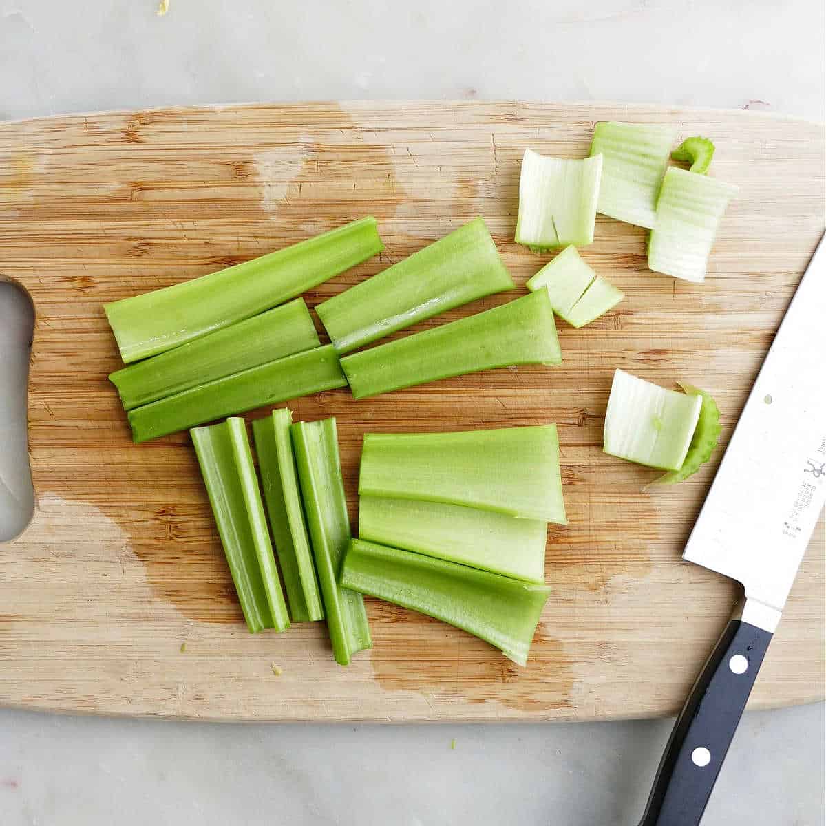 celery cut into sticks for stuffing on a cutting board with knife