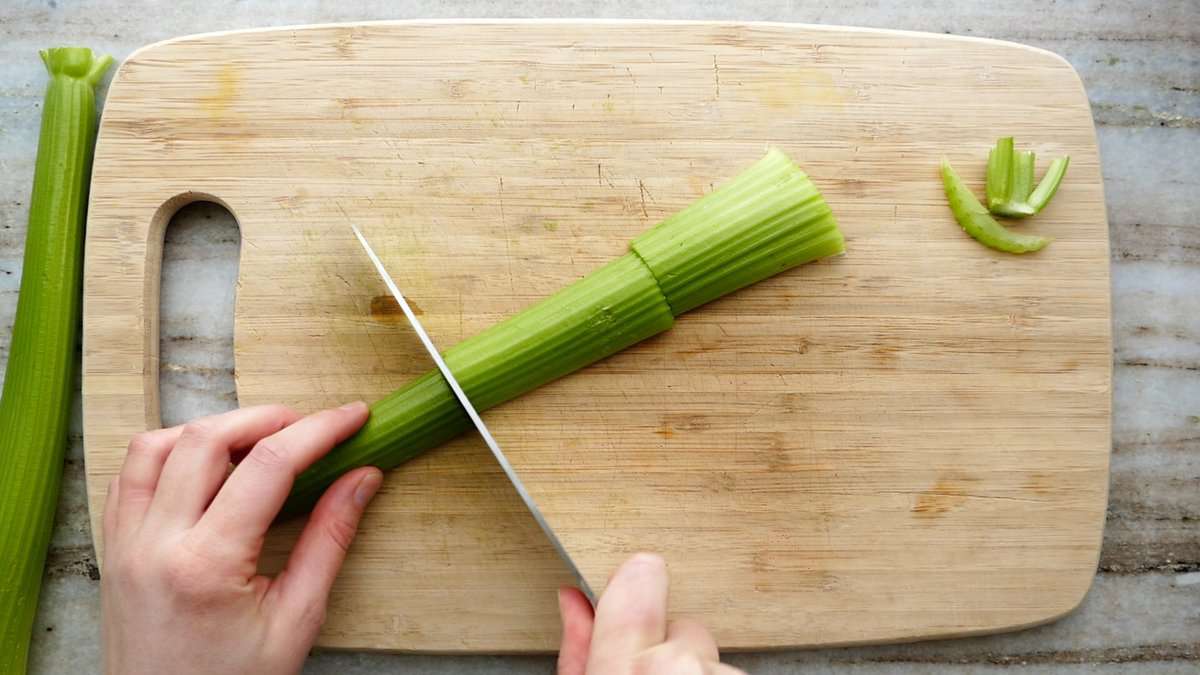 woman slicing a stalk of celery into thirds