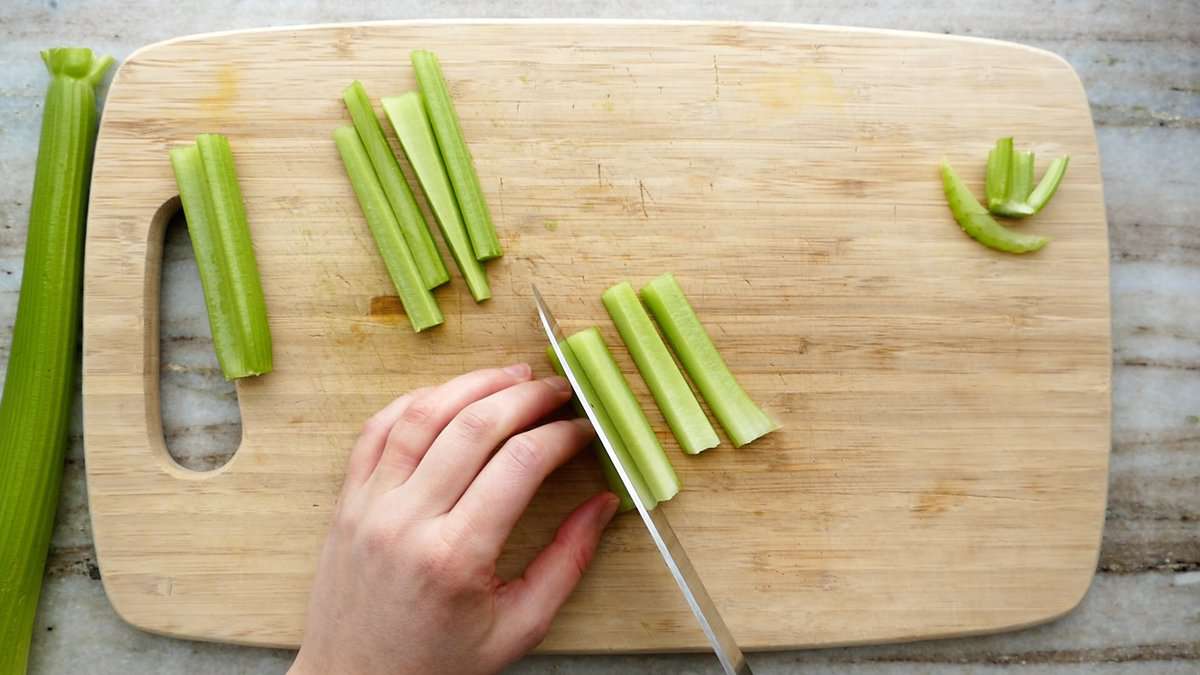 woman slicing celery into thin sticks or batons