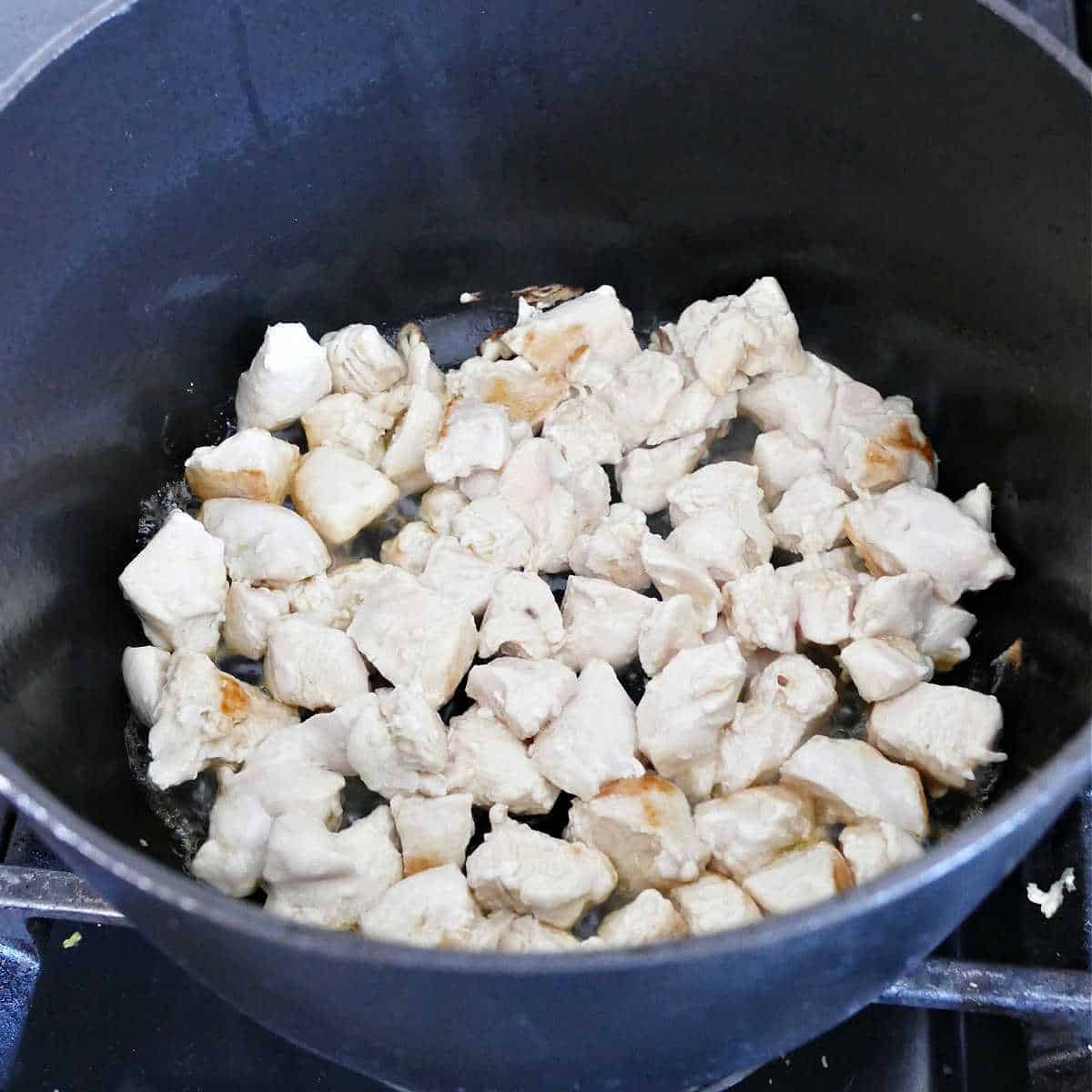 chicken breast cubes cooking in a soup pot on a stove