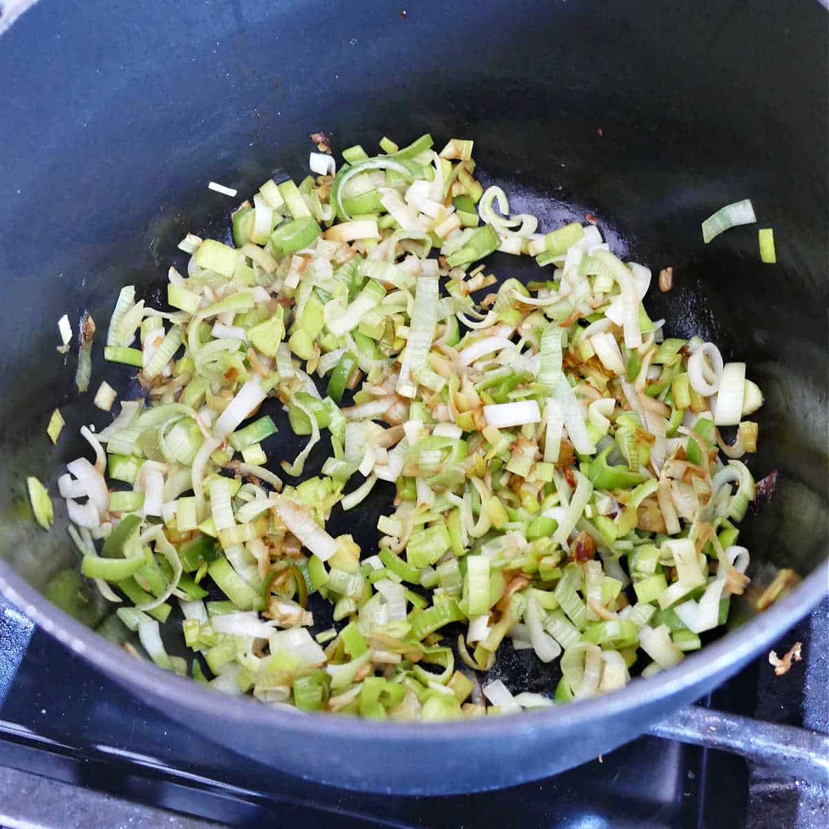 leeks cooking in a soup pot on a stove