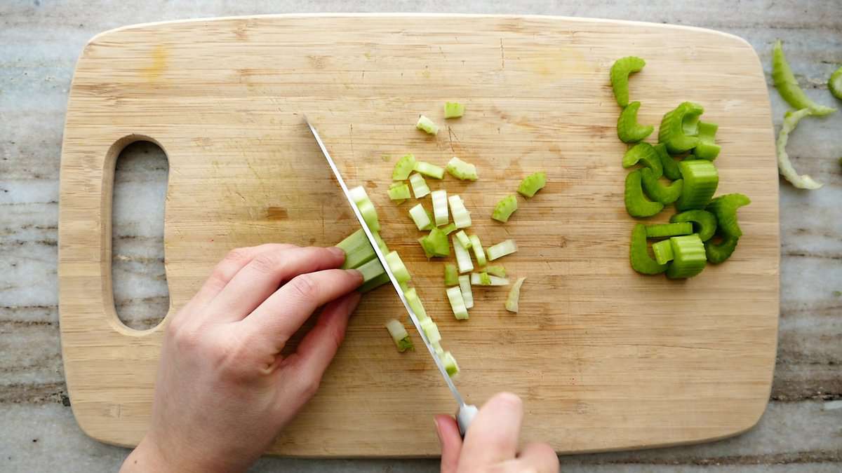 woman dicing celery on a cutting board