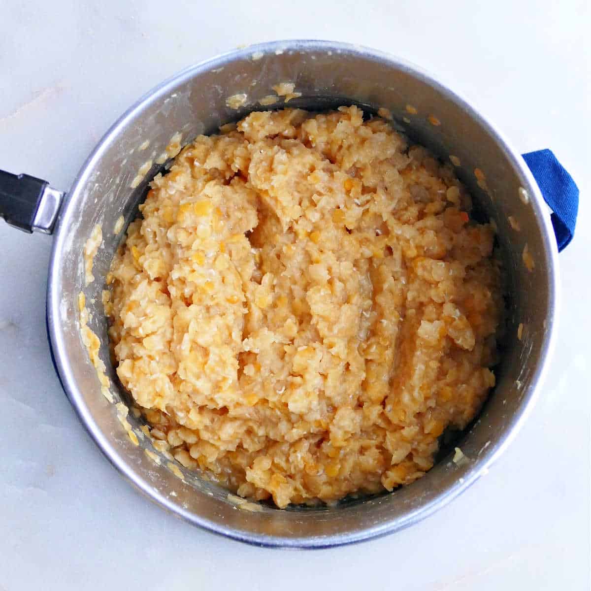 cooked red lentils in a saucepan on an oven mitt on a counter