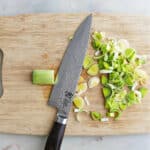 cutting board with sliced leeks and a chef's knife