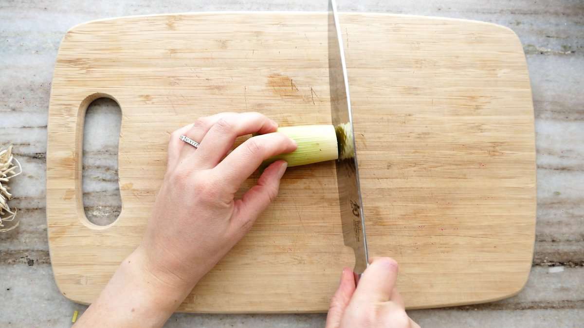 woman slicing a leek into circles on a cutting board