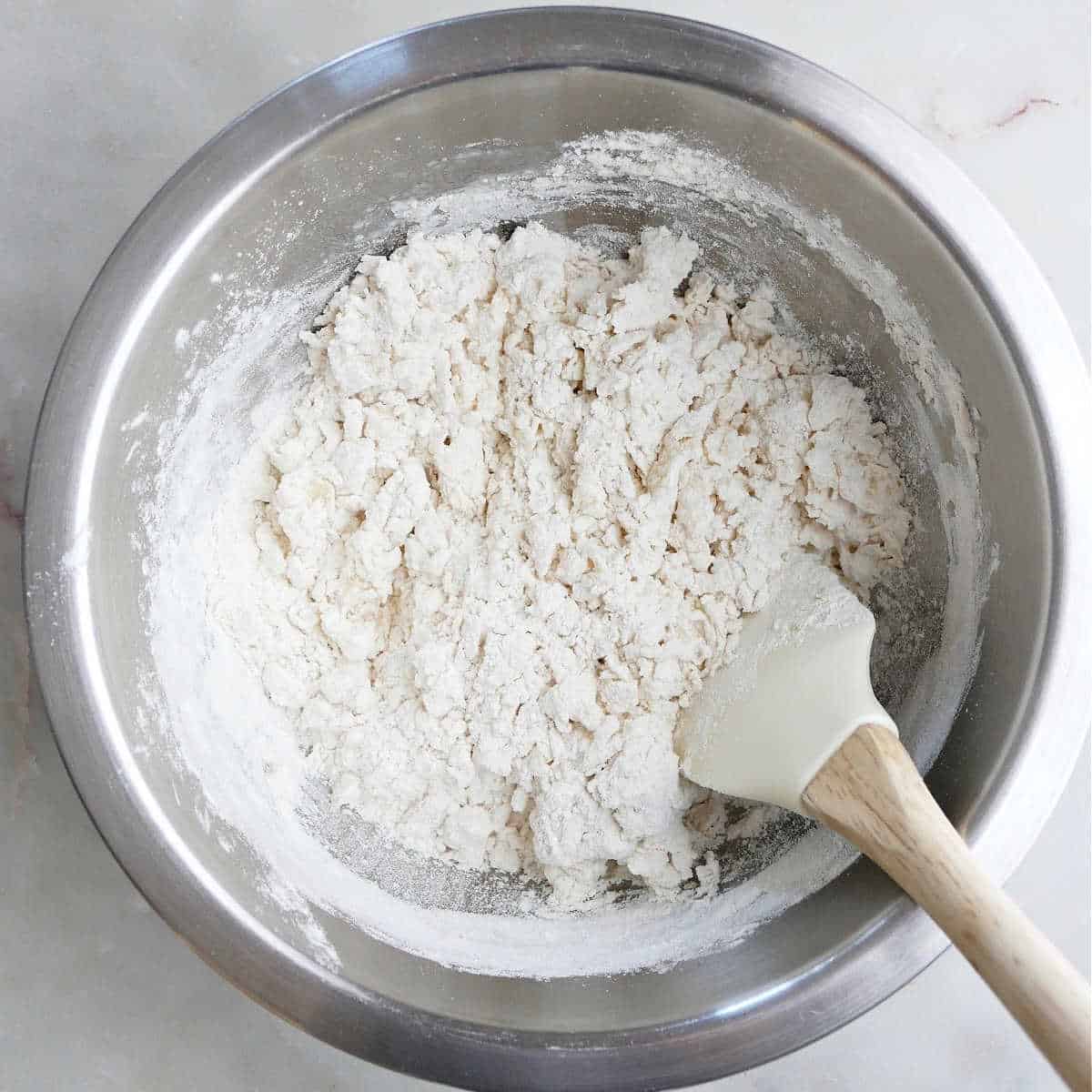 flour being mixed with boiling water in a bowl with a rubber spatula
