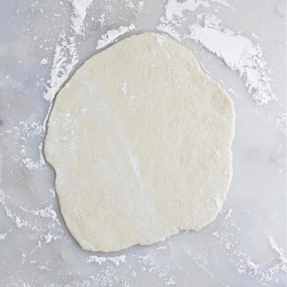 dough rolled out into a circle on a floured surface