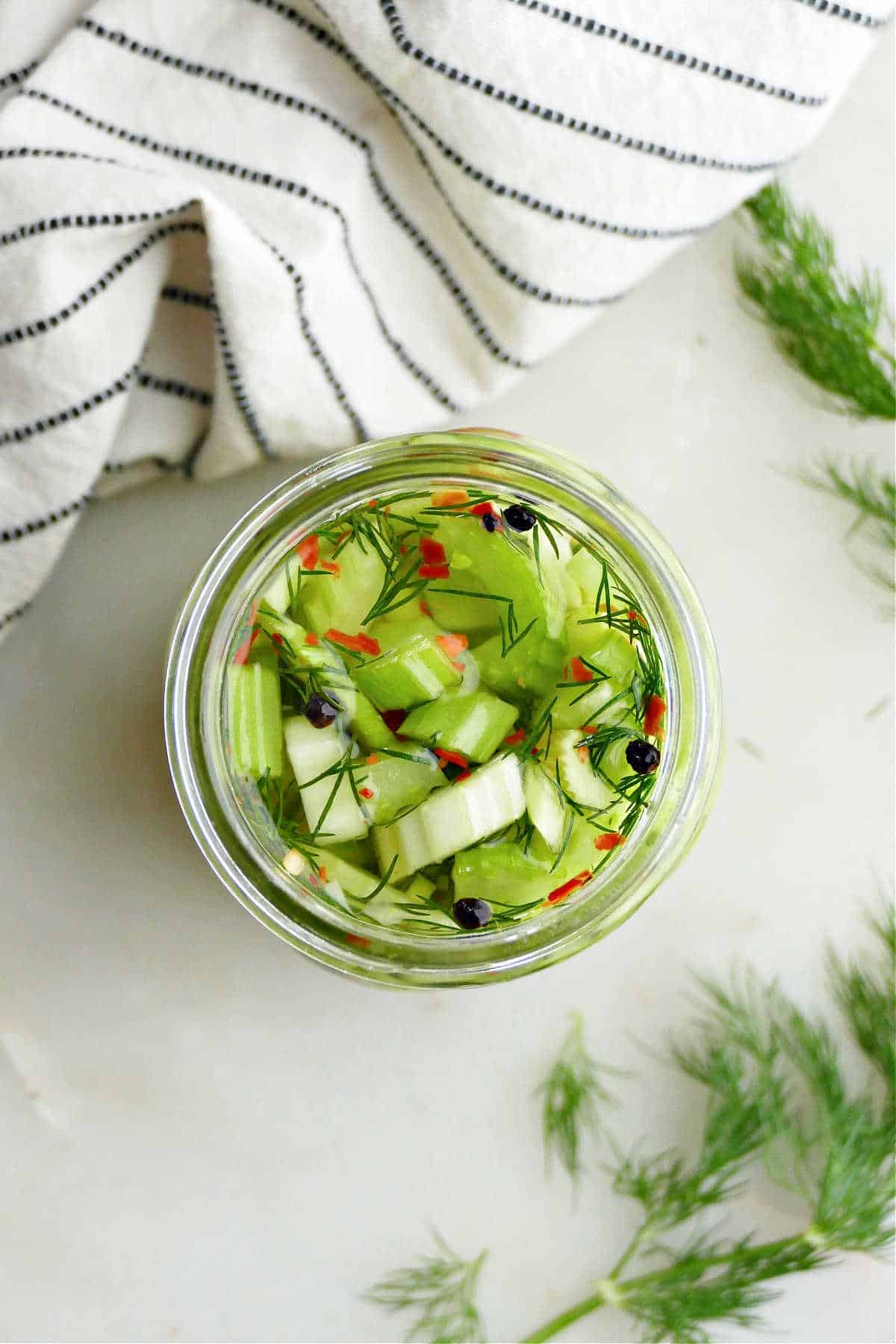 pickled celery in a jar with brine and spices on a counter
