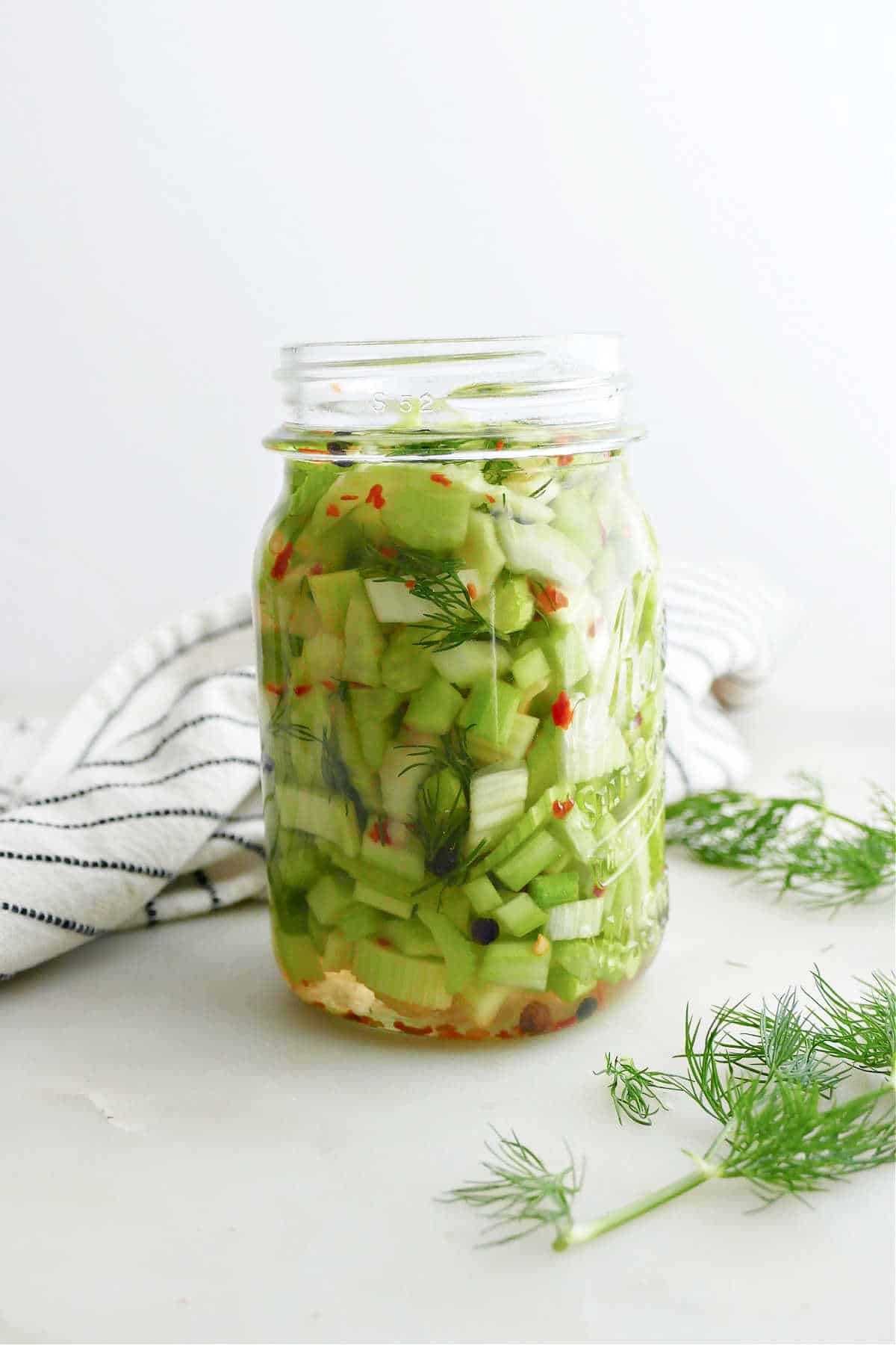 pickled celery in a jar in front of a white background
