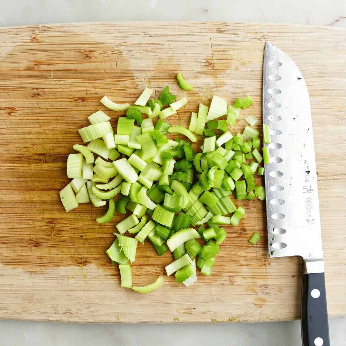 celery cut into slices on a cutting board with knife