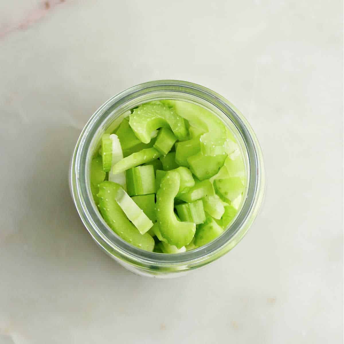 cut celery stuffed into a glass jar on a counter