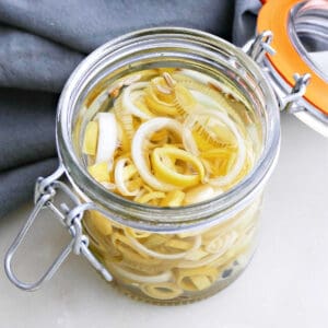 pickled leeks in a jar on a counter next to a napkin