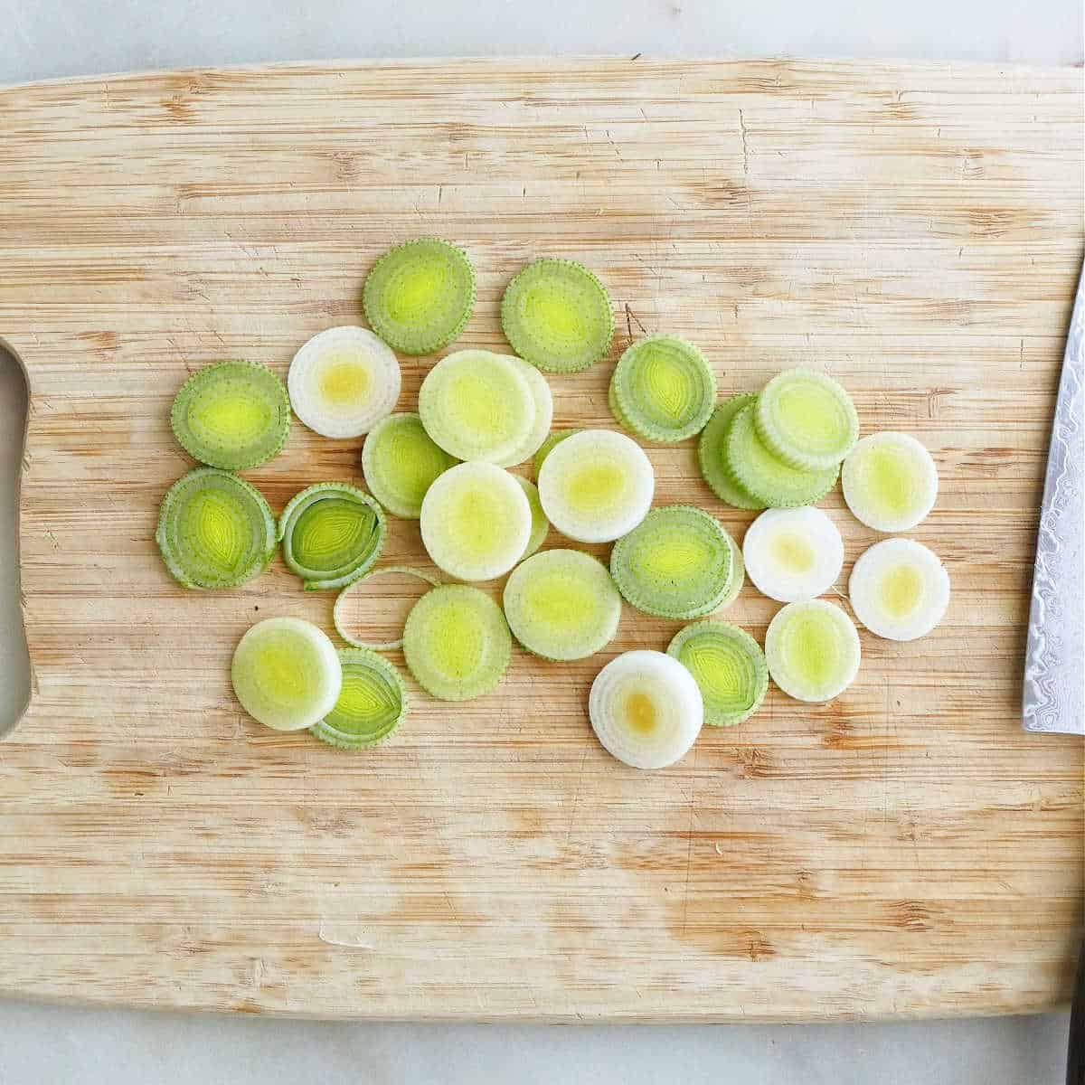 leeks sliced into circles on a cutting board with a knife