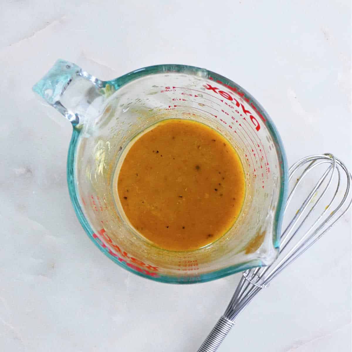 olive oil whisked with honey, lemon juices, and spices in a measuring cup