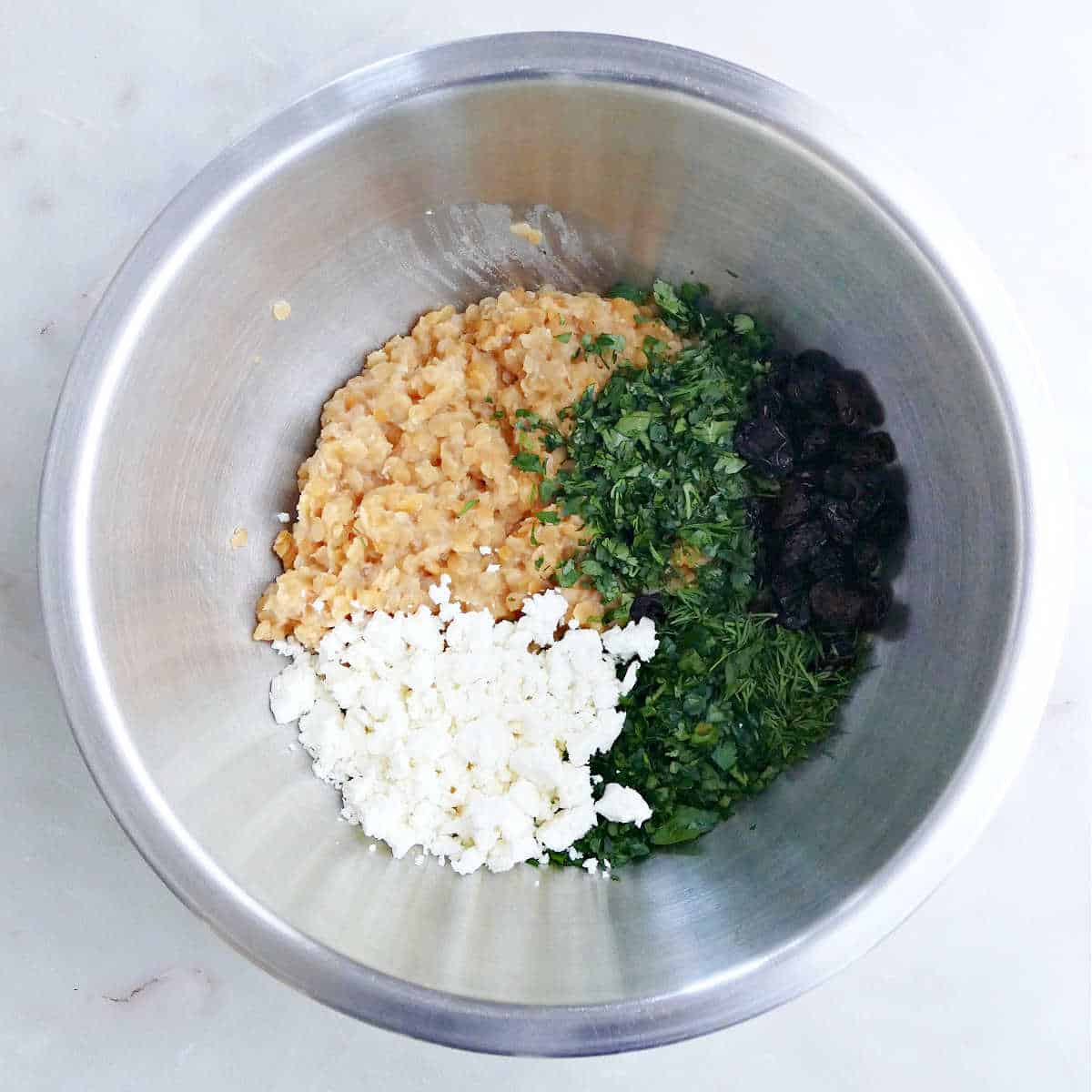 red lentils, feta cheese, herbs, and raisins in a mixing bowl