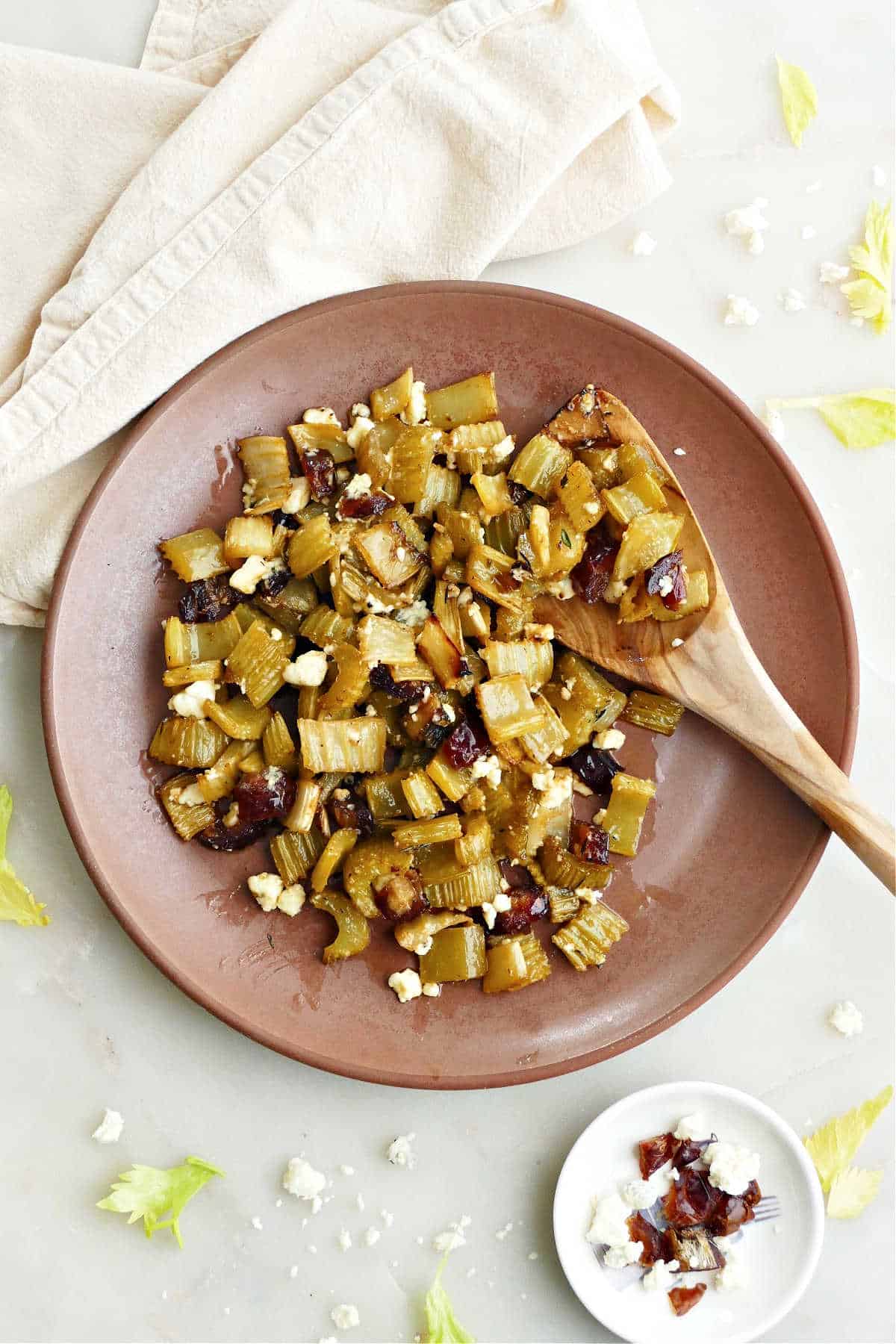 roasted celery with dates and blue cheese on a plate with a wooden spoon