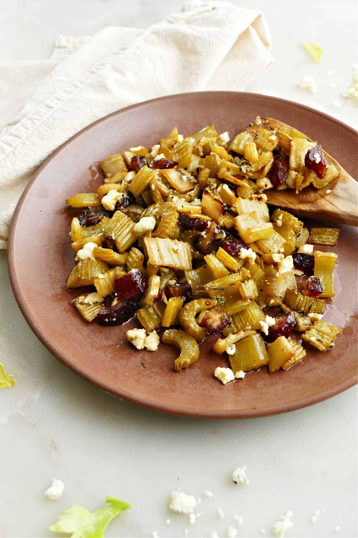 roasted celery with dates and blue cheese on a plate with a wooden spoon