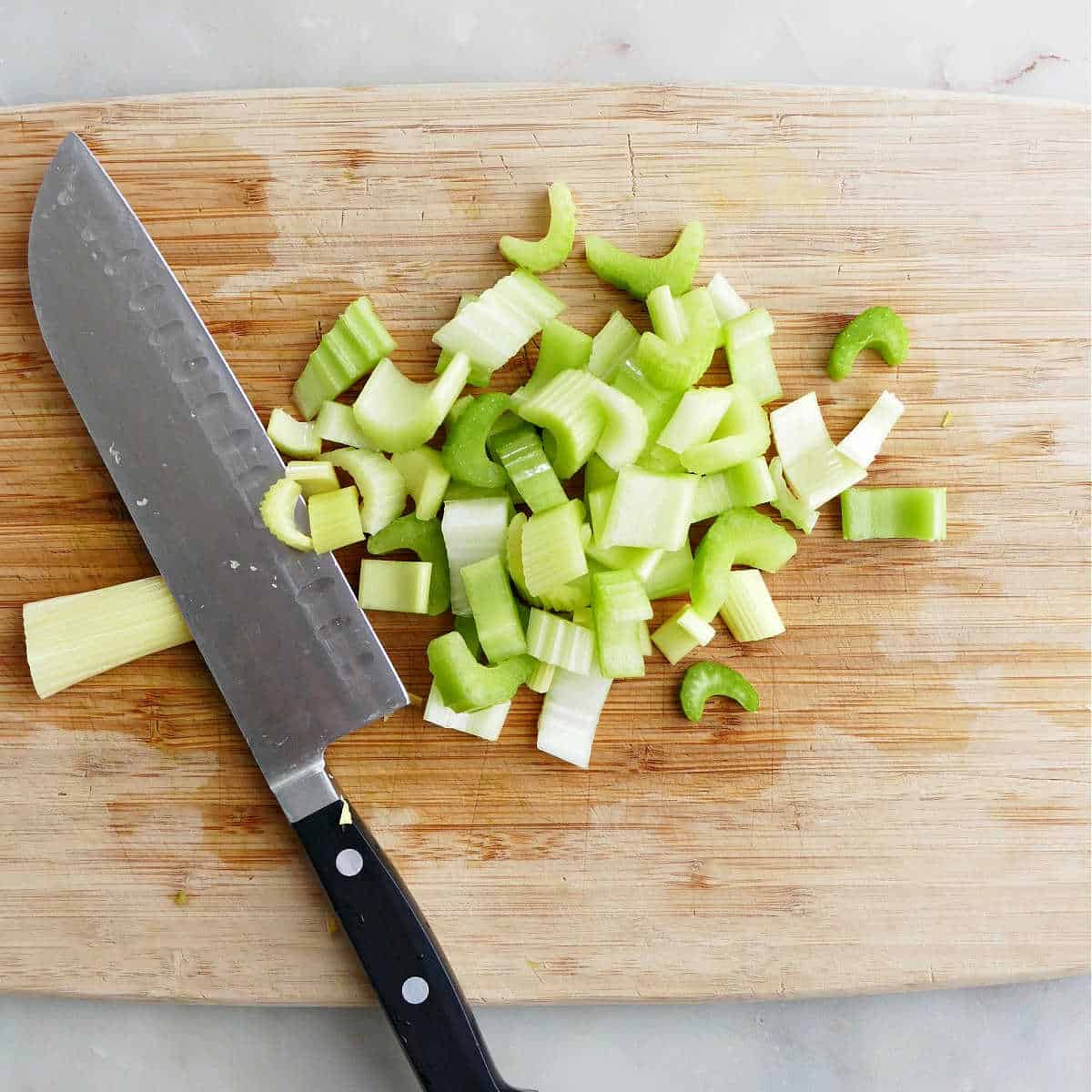 celery cut into slices on a cutting board with a chef's knife
