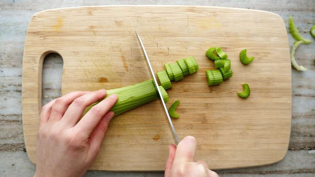 woman slicing a stalk of celery on a cutting board