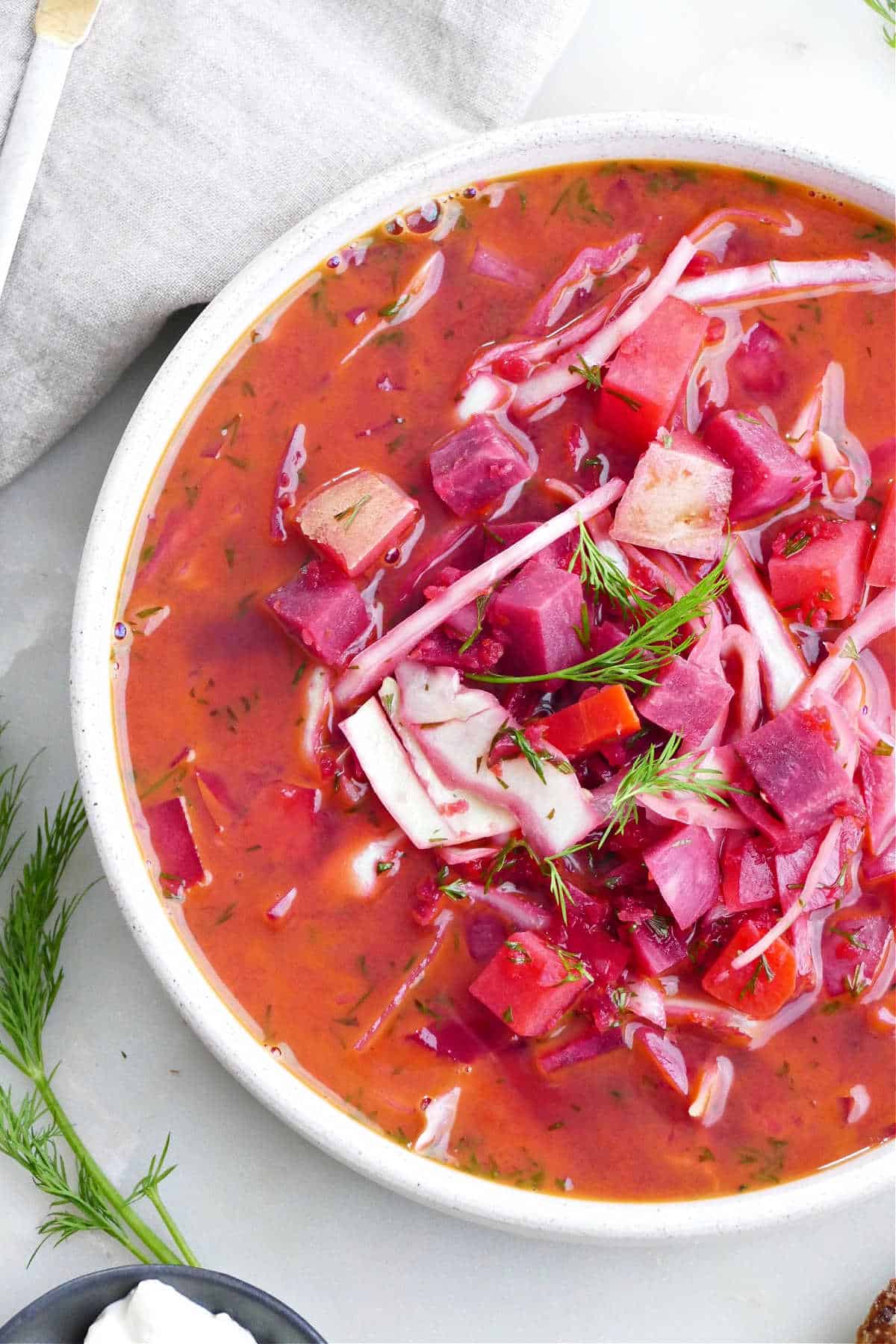 vegetarian borscht in a serving bowl topped with fresh dill