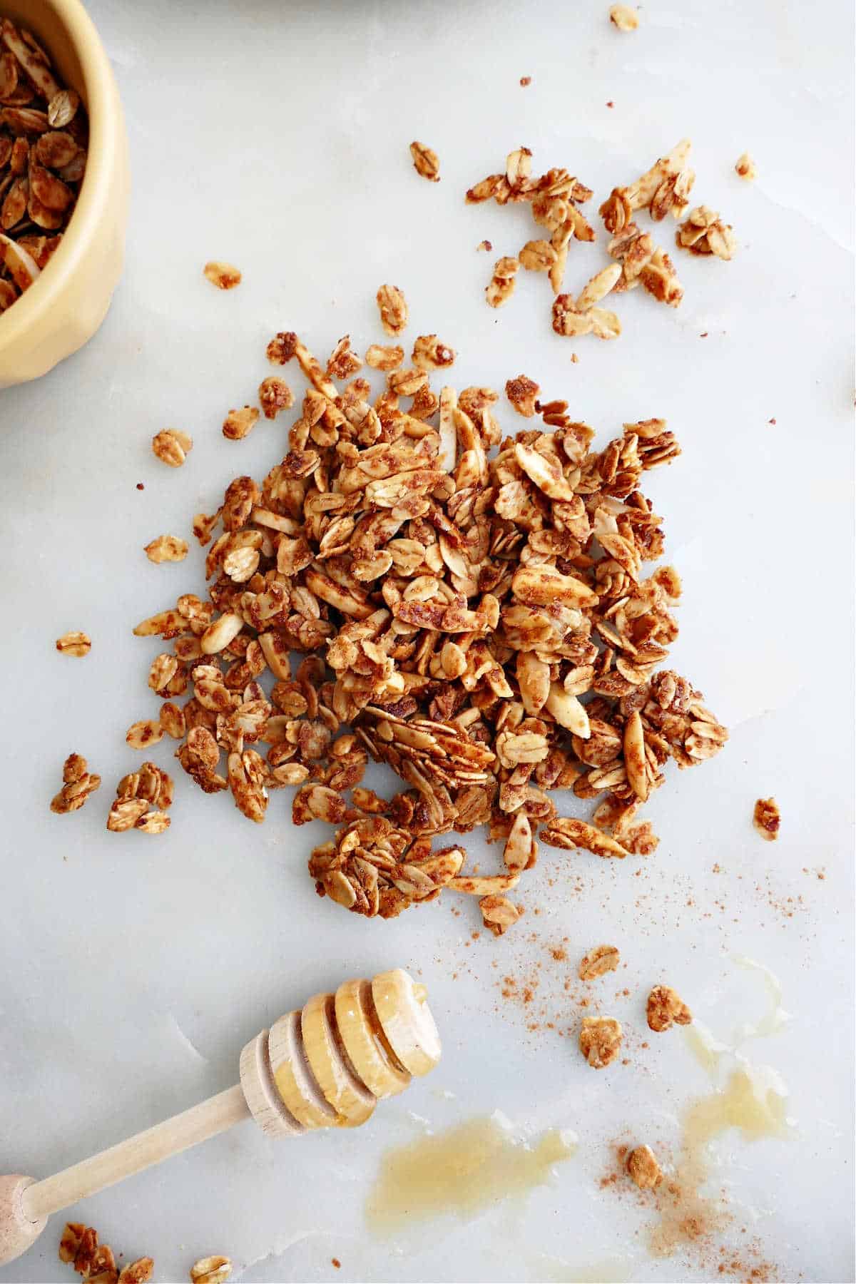 almond honey granola on a counter next to a honey dipper