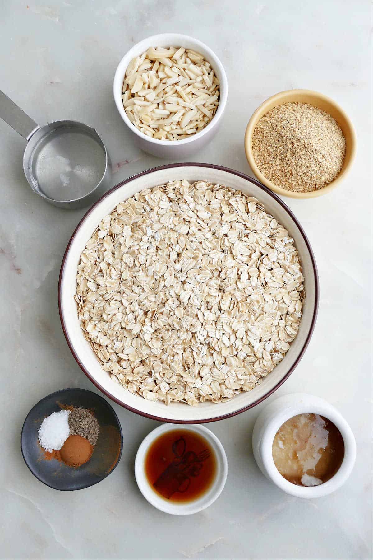 oats, slivered almonds, wheat germ, coconut oil, spices, vanilla, and honey on a counter