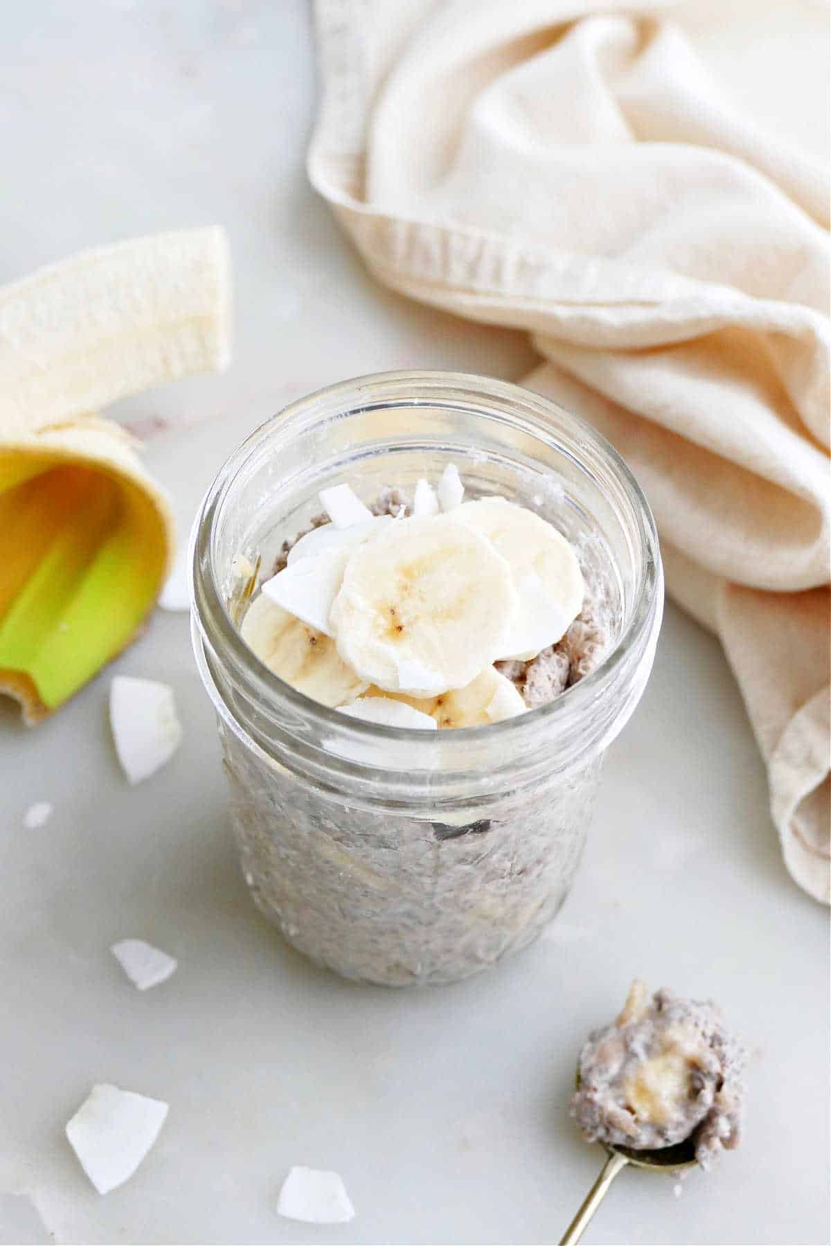 banana chia pudding topped with sliced bananas and coconut in a jar