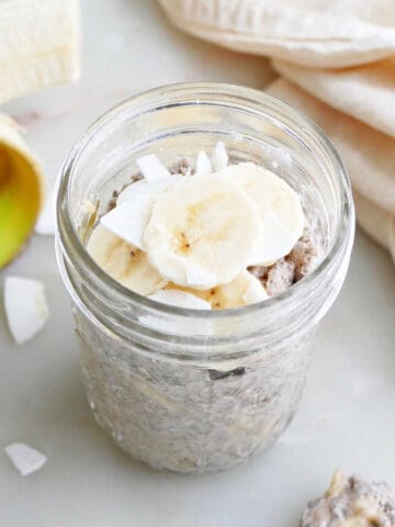 banana chia pudding topped with sliced bananas and coconut in a jar