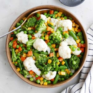 buttered vegetables in a serving bowl next to a napkin and spices