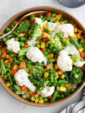 buttered vegetables in a serving bowl next to a napkin and spices