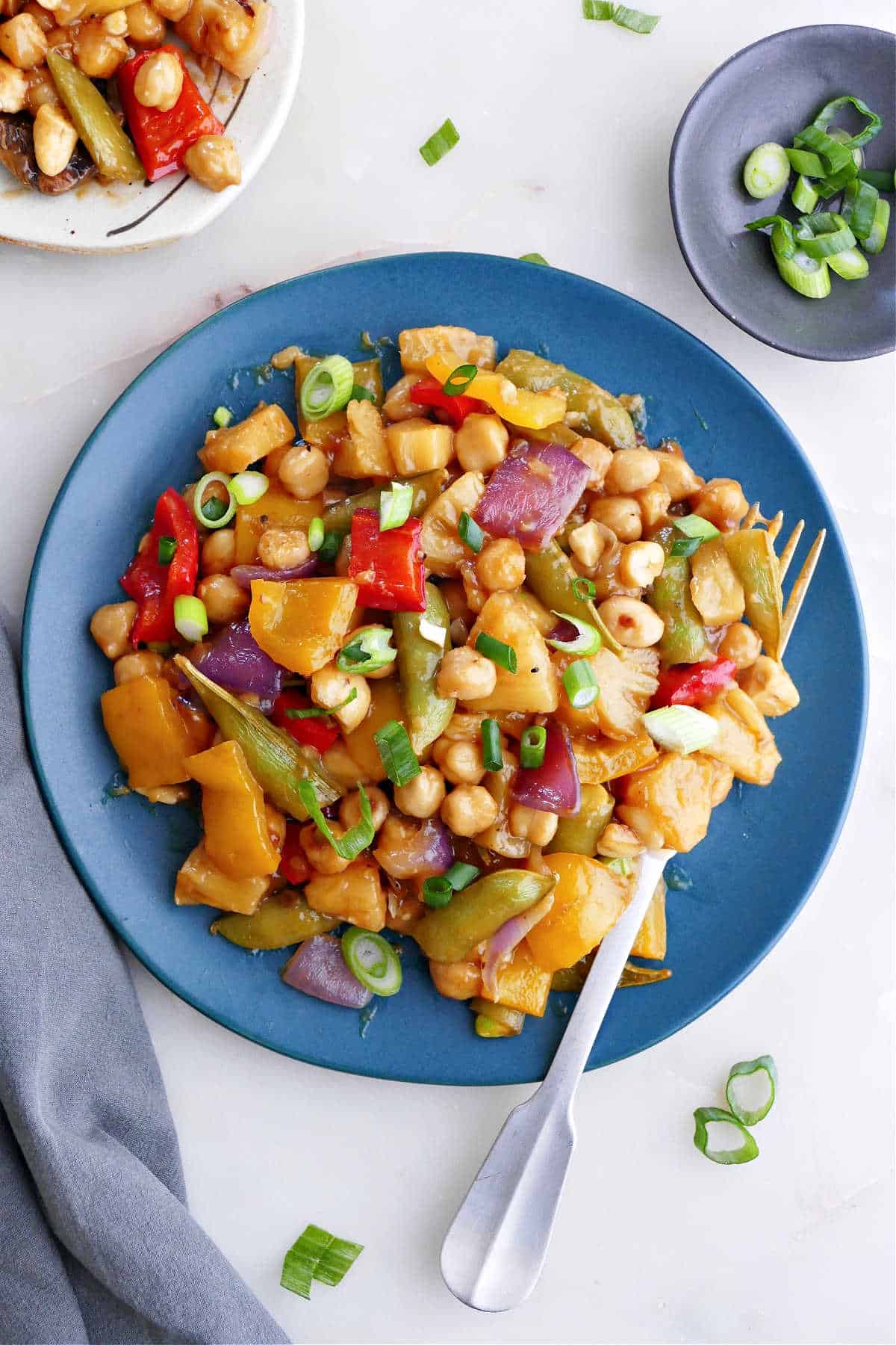 chickpea stir fry with pineapple and vegetables on a plate with a fork