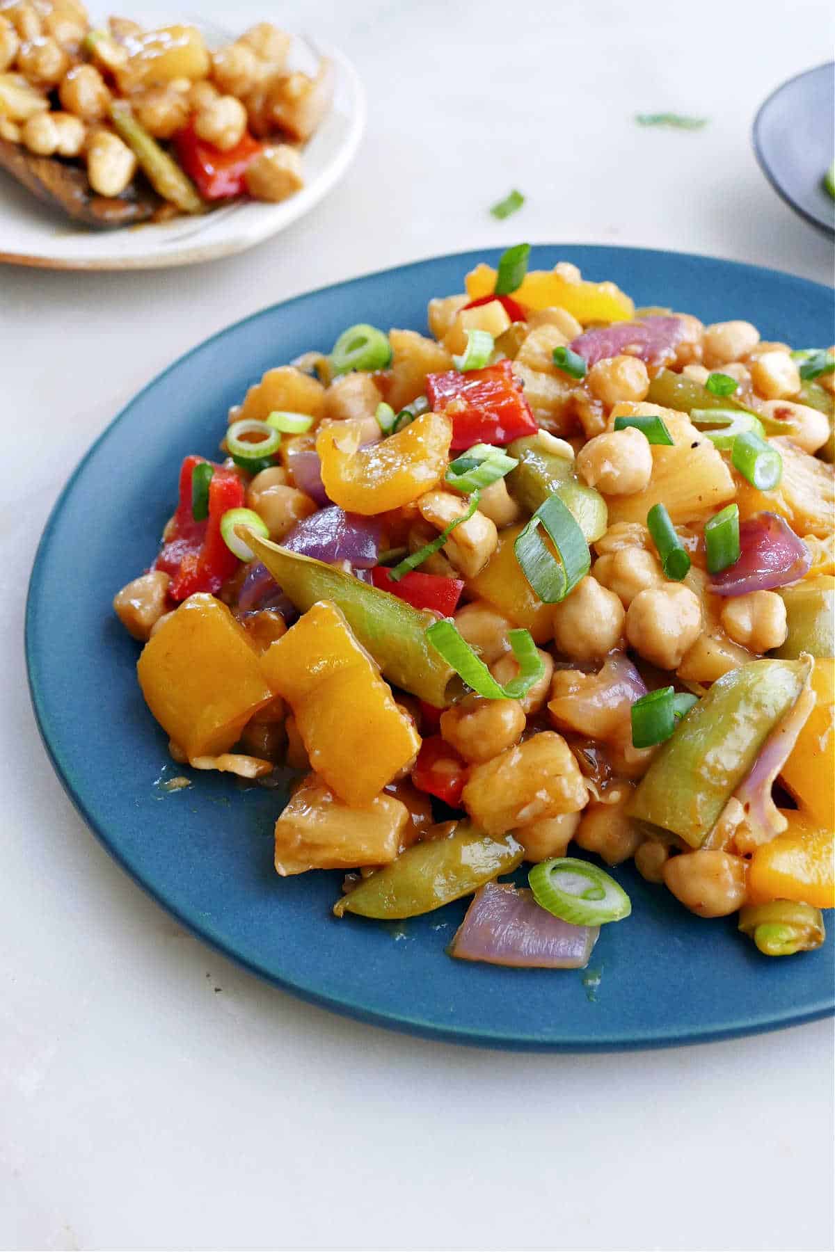 stir fry with chickpeas and pineapple on a plate topped with scallions